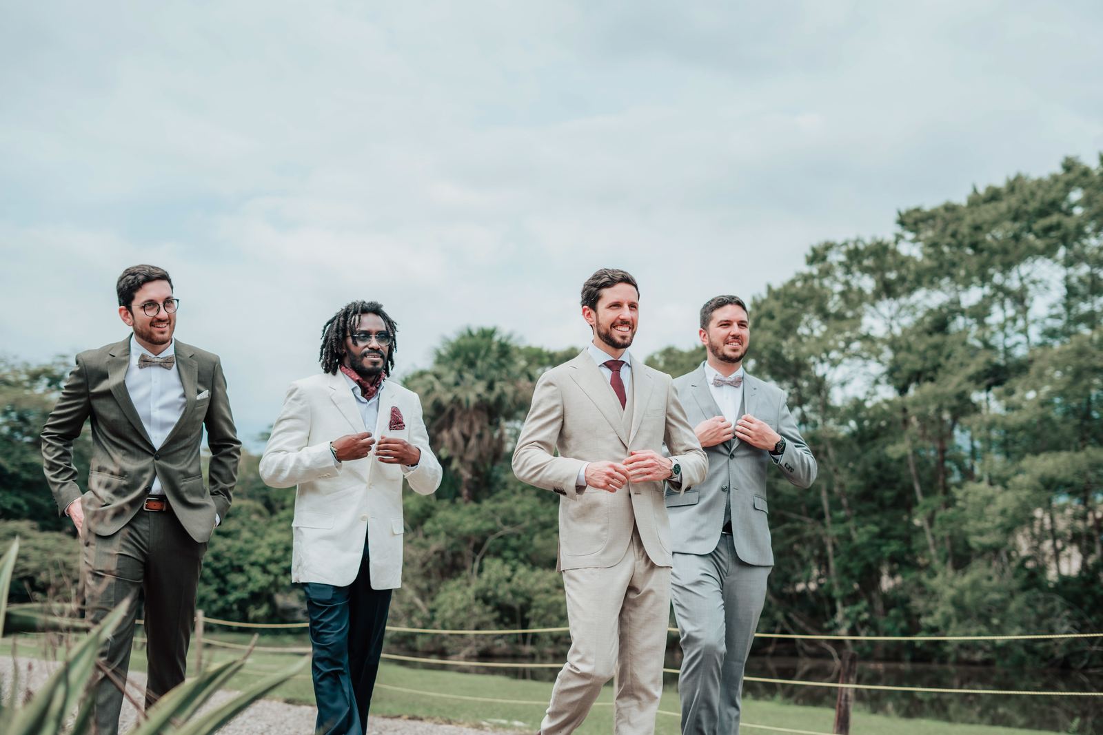 Cuatro amigos del novio caminando por un jardín