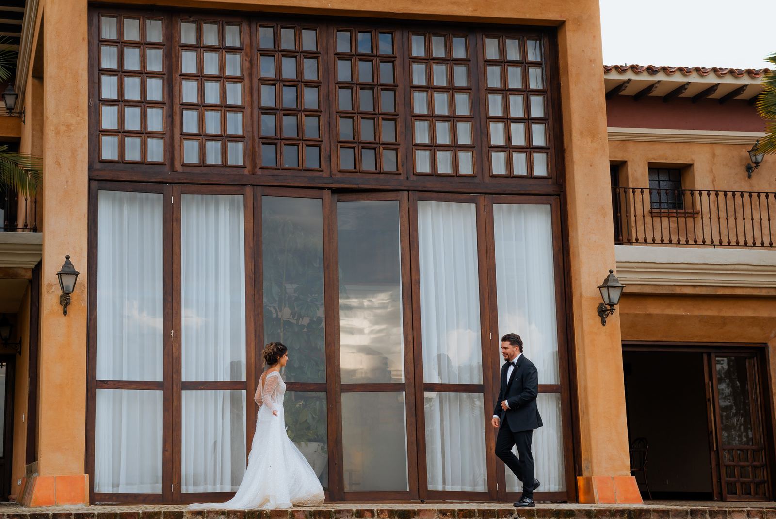 Los novios caminando uno hacia el otro frente a ventanales de madera