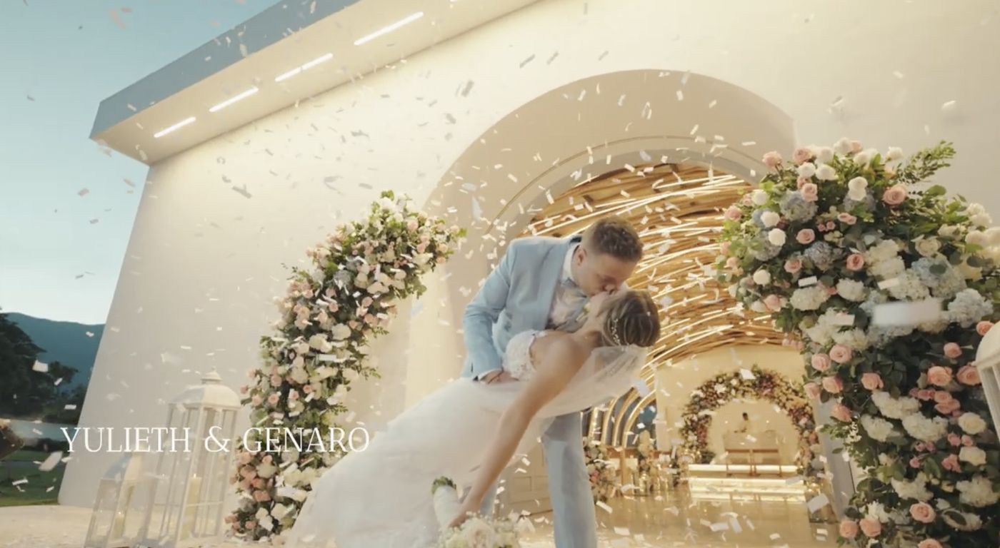 Yulieth y Genaro besándose bajo confeti frente a una capilla de flores