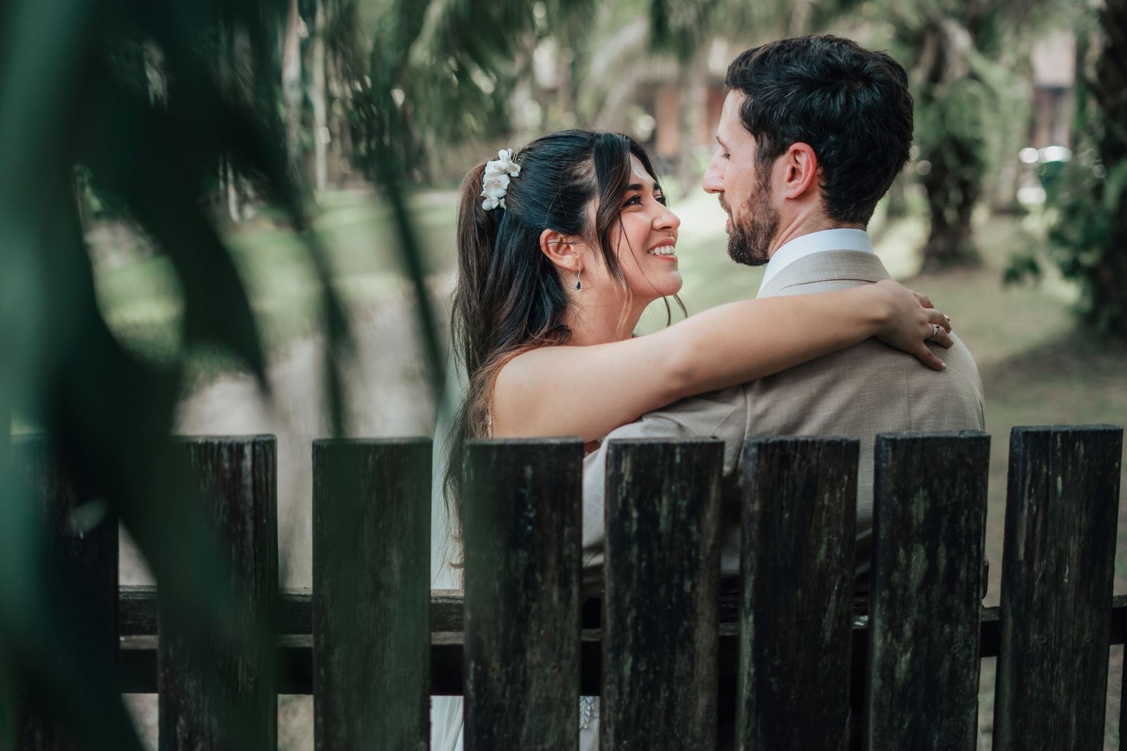 Novios abrazados detrás de una cerca de madera